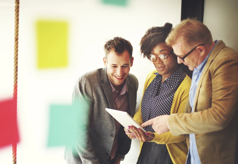 Trois professionnels en réunion collaborative dans un bureau moderne, consultant ensemble des documents
