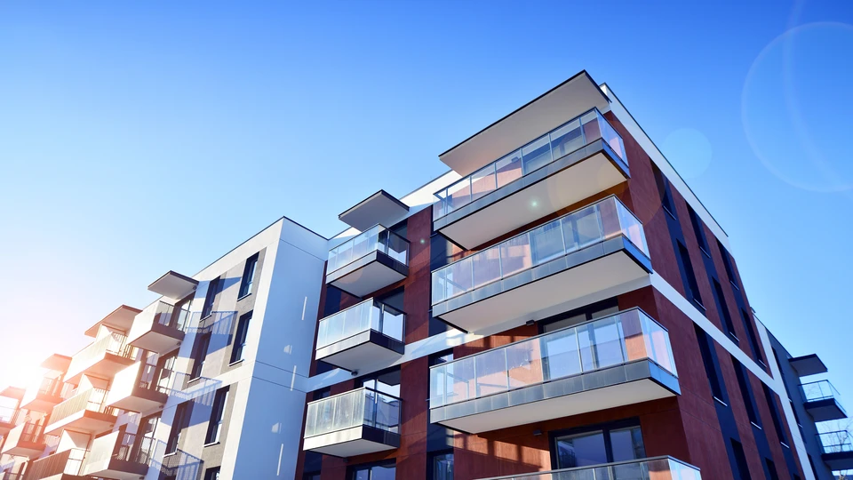 Façades d'immeubles résidentiels modernes avec balcons en saillie et grandes baies vitrées sous ciel bleu dégradé