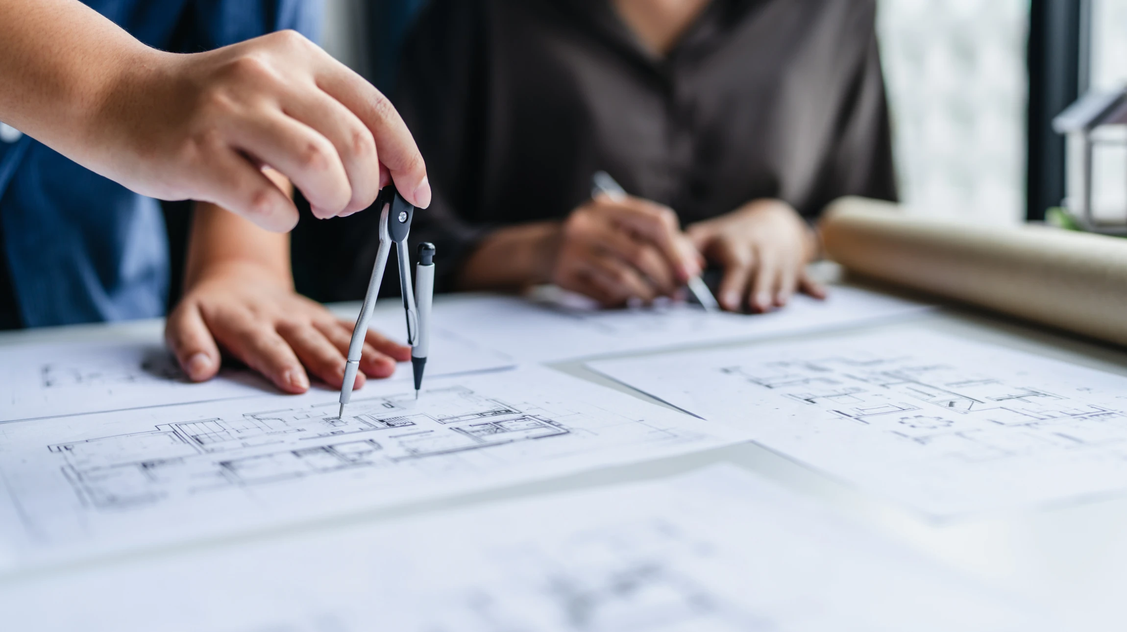 Deux professionnels analysent des plans architecturaux sur une table de travail
