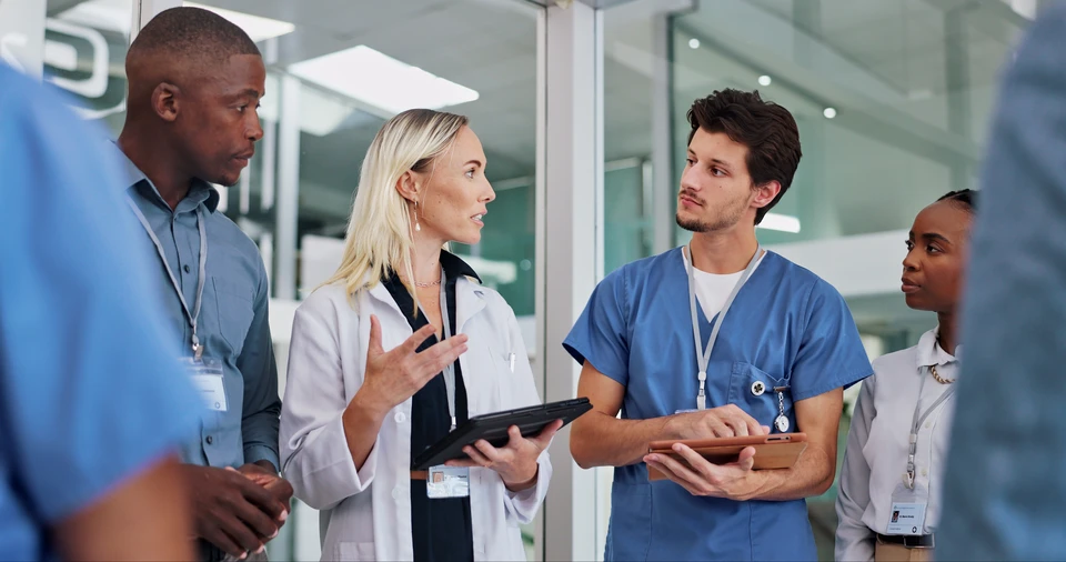 Les infirmières et un coordonnateur discutent des stratégies de soins dans une maison de soins infirmiers, favorisant le travail d'équipe et la communication dans un cadre professionnel